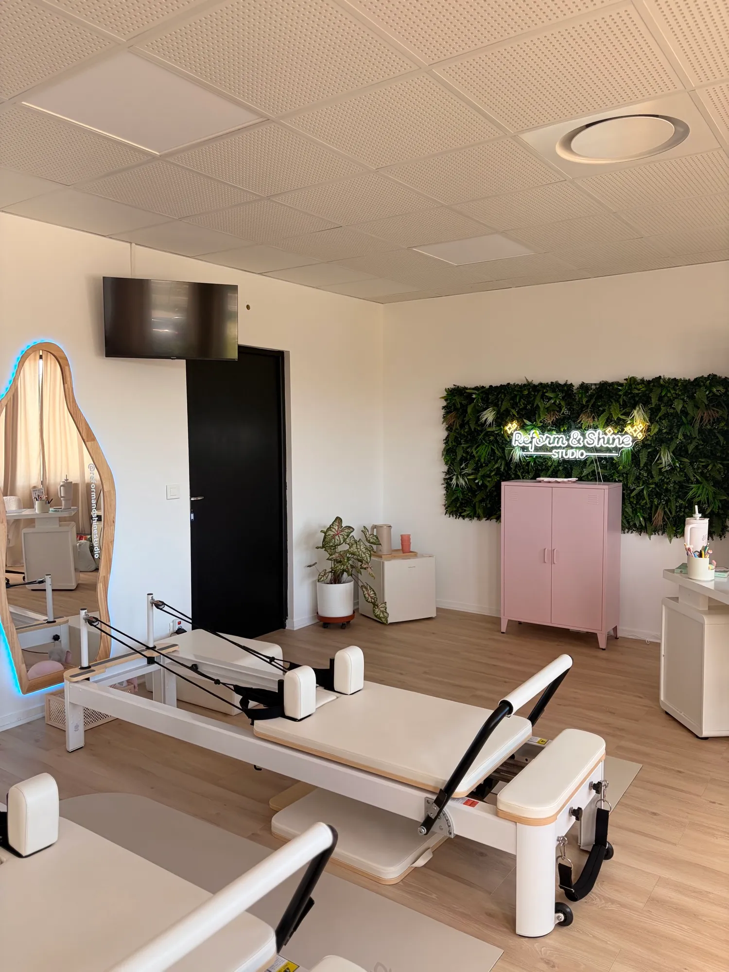 Le coin du studio : mur végétal, enseigne lumineuse Reform & Shine et Reformer